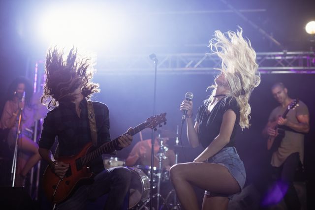 Female singer and male guitarist with tousled hair performing at nightclub - Download Free Stock Photos Pikwizard.com