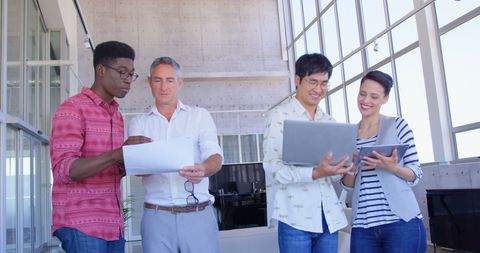 Diverse Team Collaborating with Documents and Laptops in Modern Office