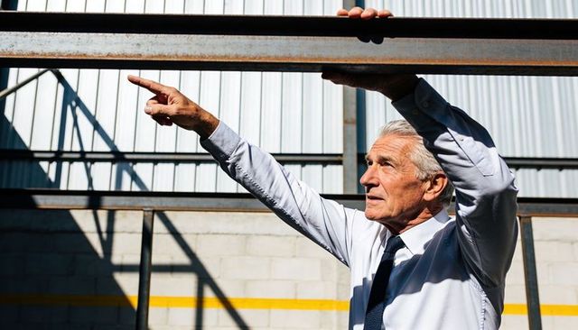 Senior supervisor inspecting steel beam and pointing in industrial warehouse safety check