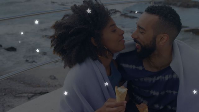 Romantic and cozy seaside moment featuring a couple enjoying ice cream, wrapped in blanket, with animated stars adding whimsy. Ideal for advertising romance-themed products, travel agency promotions, or social media content related to couples and intimacy.