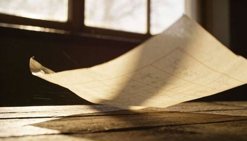 Loose gridded paper floating over worn wooden table in golden backlight