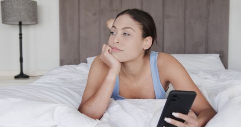 Relaxed Woman Using Smartphone on Cozy Bed