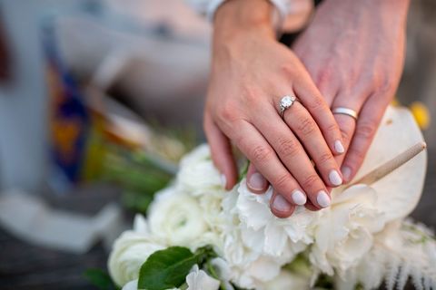 Close-up of Married Couple's Hands Over Wedding Flowers