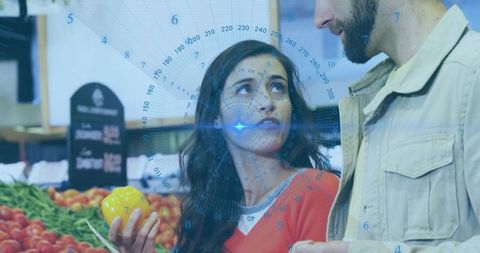 Couple shopping at market using augmented reality hud while woman selecting yellow pepper