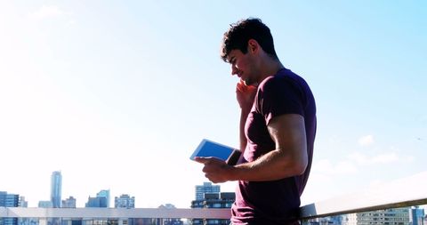 Man Focused on Balcony Using Tablet and Smartphone