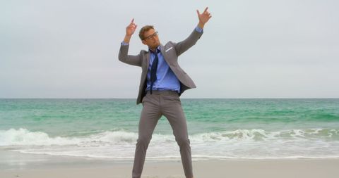 Businessman joyfully dancing on beach during work break