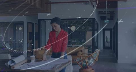 Focused woman analyzing blueprints in modern office