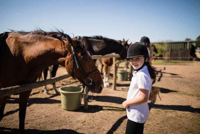 Smiling girl standing near the horse in ranch on a sunny day