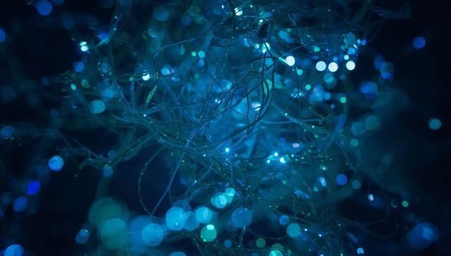 Glowing fiber-optic tangles scattering cool blue and teal light with bokeh glow macro