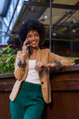 Confident Businesswoman Smiling While Talking on Smartphone in Modern Office