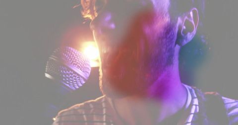 Male Musician Singing on Stage with Dramatic Lighting