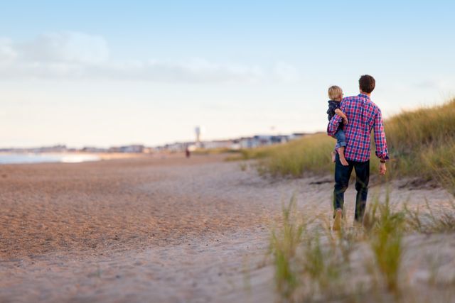 Father Carrying Child Walking Along Sandy Beach - Download Free Stock Images Pikwizard.com