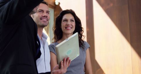 Real estate agent presenting new home to smiling couple