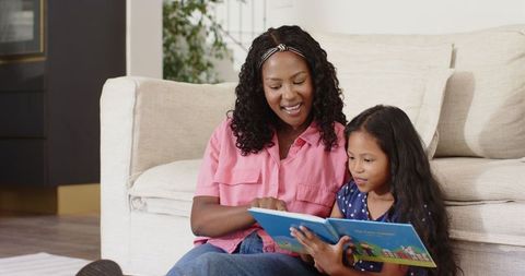 Mother and Daughter Reading Storybook Together at Home