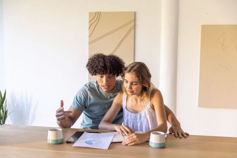 Young diverse couple reviewing finances and planning at bright minimalist kitchen table