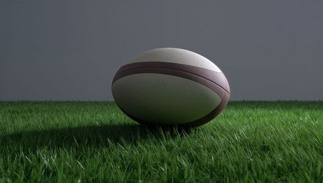 American Football Resting on Grass Against Grey Backdrop