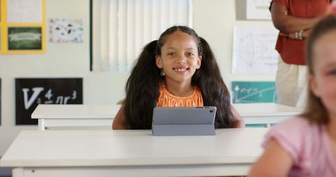 African American elementary school girl smiling and using tablet in classroom