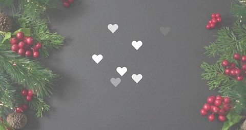 Framing six white paper hearts on charcoal board with evergreen sprigs and red berries