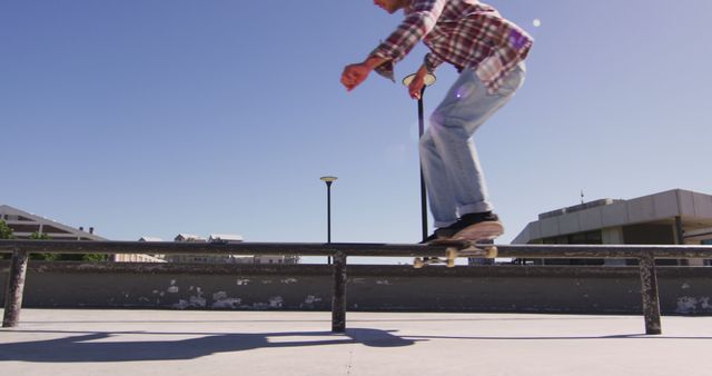 Skilled skateboarder is performing a balance move while grinding over a metal rail in a skatepark. This can be used to represent outdoor activities, youth culture, skateboarding tricks, and action sports. Ideal for articles and advertising campaigns that focus on sports performances, outdoor urban activities, and skillful stunts.