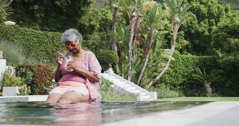 Joyful Senior Woman Relaxing by Outdoor Poolside with Drink