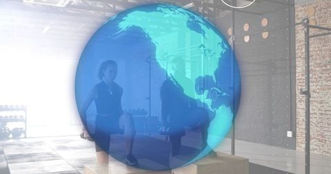 Partners Performing Plyometric Box Jumps in Industrial Gym with Globe Overlay for Global Fitness