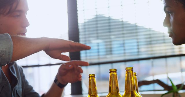 Friends drinking and talking at table with beer bottles - Download Free Stock Images Pikwizard.com