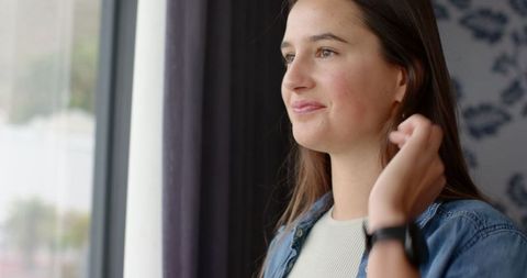 Young Woman Peacefully Gazing Out Large Window at Home