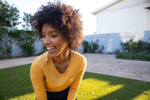 Joyful Woman Laughing Outdoors in Vibrant Yellow Attire