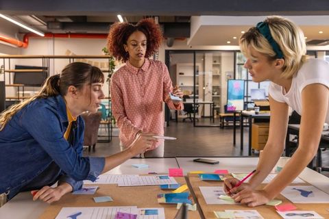 Creative Female Team Brainstorming with Sticky Notes in Modern Workspace