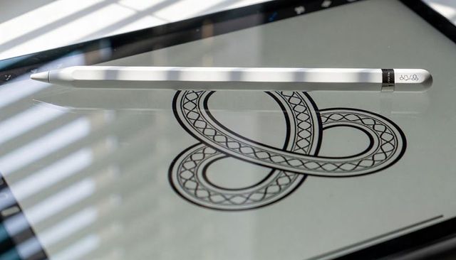 Sleek silver stylus resting on glossy tablet showing ornamental line art and reflections