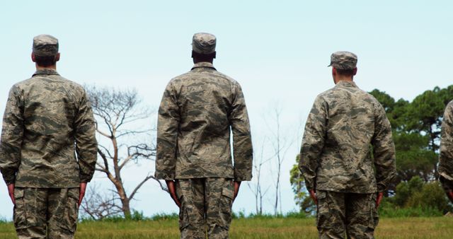 Soldiers in camouflage uniforms standing in line outdoors. Ideal for use in articles about military service, discipline, army training, or soldier life. Can be used in contexts discussing national defense, patriotic events, and veteran affairs.