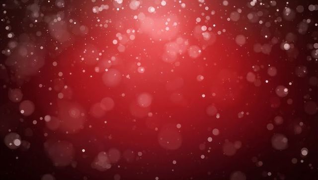 Glowing red bokeh with soft pink orbs and sparkling particles for festive background