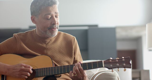 Older man playing acoustic guitar in living room - Download Free Stock Images Pikwizard.com