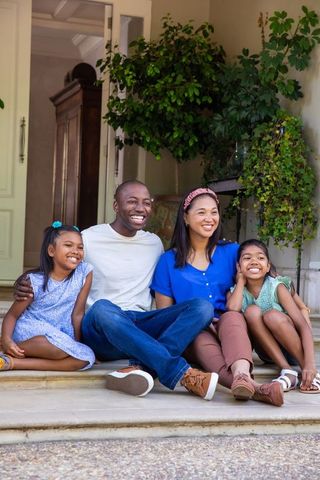 Happy Family Relaxing on Front Porch in Sunny Weather
