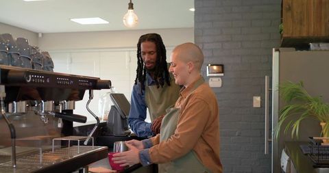 Diverse baristas preparing espresso and steaming milk at modern industrial cafe counter