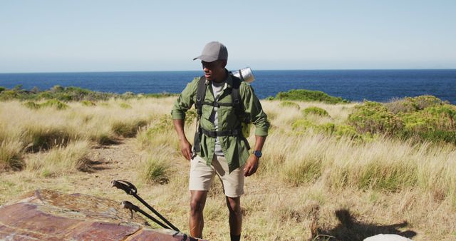 African american man hiking in countryside by the coast taking a rest. fitness training and healthy outdoor lifestyle.