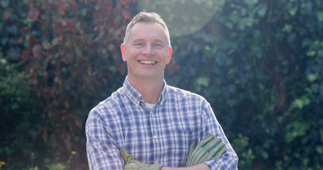 Smiling Man with Gardening Gloves in Sunlit Garden - Download Free Stock Images Pikwizard.com