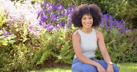 Smiling Woman Enjoying Sunny Day in Flower Garden