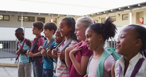 Diverse children with backpacks smiling outdoors at school