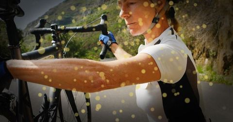Dedicated cyclist adjusting road bike on mountain journey