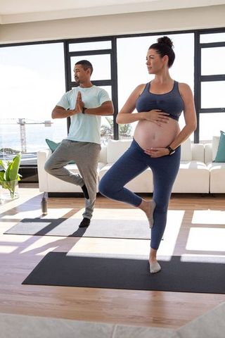 Diverse couple practicing yoga in waterfront apartment
