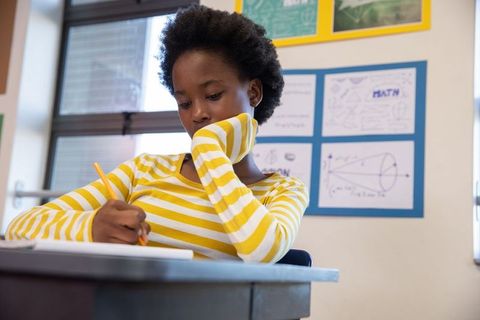 Focused teenage girl writing in classroom