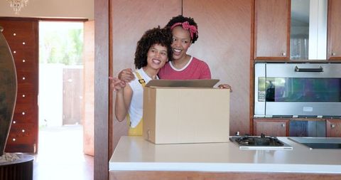 Joyful women embracing unboxing in modern kitchen