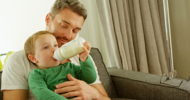 Father Feeding Toddler Son from Bottle in Cozy Living Room - Download Free Stock Images Pikwizard.com