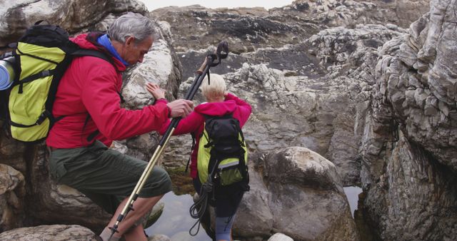 Senior couple hiking among rocky terrain with backpacks and trekking poles - Download Free Stock Images Pikwizard.com