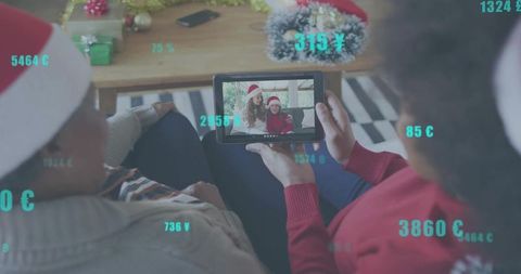 Multigenerational family watching virtual holiday call on tablet with festive currency overlays