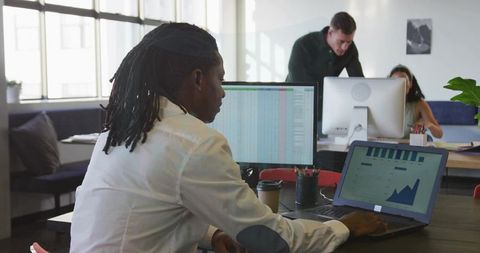 Young Professional Analyzing Data on Laptop in Modern Office