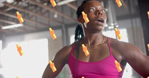 African American woman catching breath after intense workout in sunlit brick gym wearing pink top