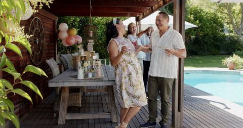 Multicultural gathering by poolside with drinks and laughter