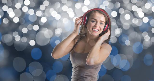 Photo of a young woman smiling while wearing headphones and enjoying music. Ideal for representations of happiness, leisure activities, music enjoyment, young lifestyle, and festive celebrations. Suitable for use in advertising for music products, lifestyle blogs, event promotions, and social media content.